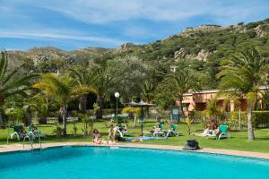 a group of people sitting around a pool at a resort at Hotel Punta Sur in Tarifa