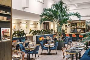 ein Restaurant mit Tischen und Stühlen und einer Palme in der Unterkunft PLEY Hotel in Paris