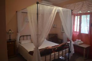 una camera con letto a baldacchino e tende bianche di Casa Montegri a Hal Ghaxiak