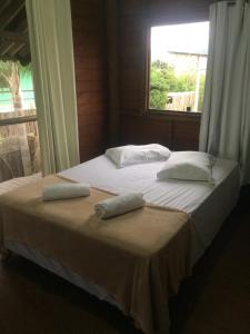 1 cama con 2 almohadas y ventana en Linda casa na Gamboa Garopaba, en Garopaba