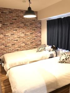 2 camas en una habitación con una pared de ladrillo en River Side Namba 400, en Osaka