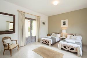 a bedroom with two beds and a chair and a mirror at Hotel Punta Sur in Tarifa