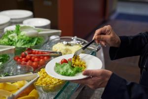 a person holding a plate of food with a fork and knife at Sotetsu Fresa Inn Higashi Shinjuku in Tokyo