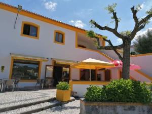 an orange and white building with a tree and an umbrella at Porto D'Abrigo - Alojamento Local in Sardoal