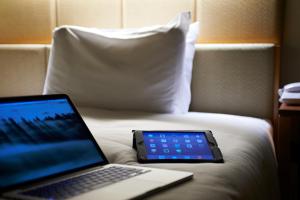 a laptop and a tablet sitting on top of a bed at Sotetsu Fresa Inn Higashi Shinjuku in Tokyo
