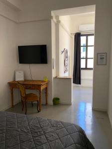 een slaapkamer met een bureau en een televisie aan de muur bij Palazzo Pilo in Sassari