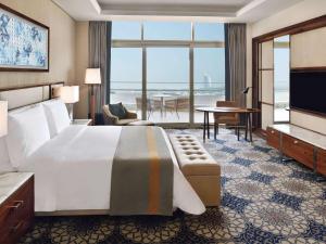 ドバイにあるGrand Plaza Mövenpickのベッドがあり、海が見えるホテルの部屋
