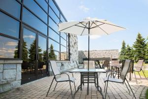 un patio con mesa, sillas y sombrilla en Hotel Le Victorin, Ascend Hotel Collection, en Victoriaville