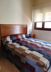 Un dormitorio con una cama con una colcha colorida. en Torrehermosa Rural en Torrehermosa