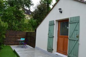 une maison avec des portes vertes, une table et une chaise dans l'établissement Les Mansardes l'Appart, à Sarlat-la-Canéda