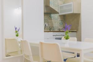 cocina blanca con mesa blanca y sillas en Apartamentos casa palacio, en El Puerto de Santa María