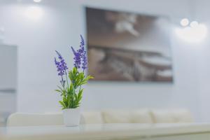 un jarrón blanco con flores púrpuras en una mesa en Apartamentos casa palacio, en El Puerto de Santa María