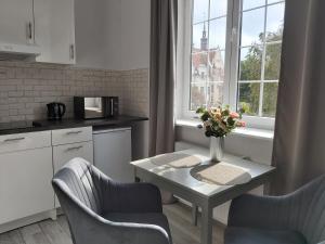 a kitchen with a table with a vase of flowers on it at BE IN GDANSK Apartments - STUDIO MARIACKA - OLD TOWN in Gdańsk