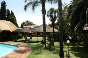 um pátio de resort com piscina e palmeiras em Aero Airport Lodge em Kempton Park