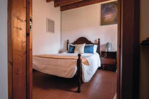 a bedroom with a bed with blue pillows at Sete Cidades House in Sete Cidades