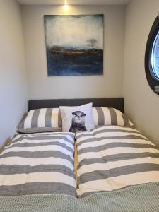 Una cama con un gato sentado encima. en Otter Comfort klasse XL Houseboat, en Ophoven