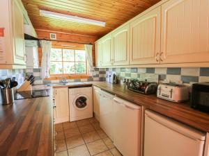 a kitchen with white cabinets and a washer and dryer at Dan Y Coed in Presteigne