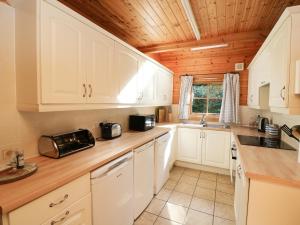 cocina con armarios blancos y techo de madera en Pen Y Clawdd, en Presteigne