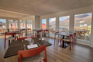 un restaurante con mesas, sillas y ventanas grandes en Hotel Disko Island en Qeqertarsuaq