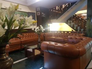 a living room with a brown leather couch and a table at Hotel Silverine in Shimla