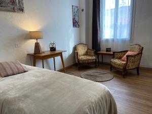 een slaapkamer met 2 stoelen en een bed en een tafel bij Les Merisiers B&B - Thorenc in Thorenc
