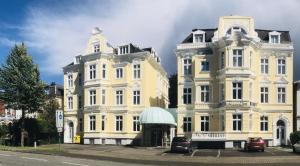 two large white buildings with cars parked in front of them at Hotel Kaiserhof Deluxe in Lübeck