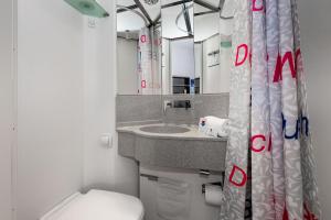 a bathroom with a toilet, sink, and mirror at Cabinn Aalborg in Aalborg