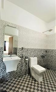 a bathroom with a sink and a toilet and a mirror at White Shell Beach House in Kannur