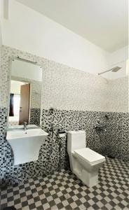 uma casa de banho com um lavatório, um WC e um espelho. em White Shell Beach House em Cananor