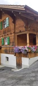 a wooden building with flowers in front of it at Mountain Village Room in Habkern