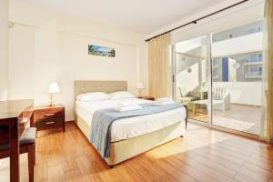 1 dormitorio con cama, escritorio y balcón en Seafront Protaras Apartments, en Protaras