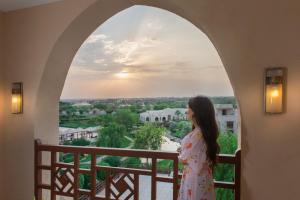a woman standing on a balcony looking out at the sunset at InterContinental Durrat Al Riyadh Resort & Spa, an IHG Hotel in Riyadh