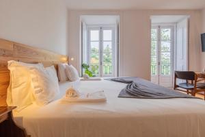 Un dormitorio con una gran cama blanca con una toalla. en Casa da Pendoa, en Sintra