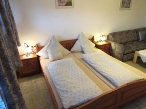 ein Schlafzimmer mit einem Bett mit zwei Kissen und einem Sofa in der Unterkunft Lohnerhof in Kirchanschöring