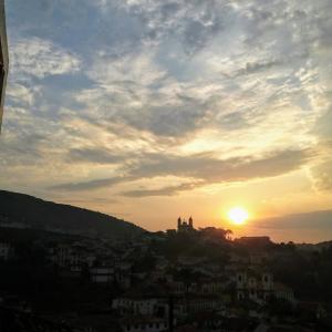 a view of the sun setting over a city at Refúgio in Ouro Preto