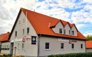 ein großes weißes Gebäude mit orangefarbenem Dach in der Unterkunft Pension Cora in Boltenhagen