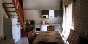 a kitchen with a table and chairs and a kitchen with white appliances at La Sérénité in Auriac-de-Bourzac