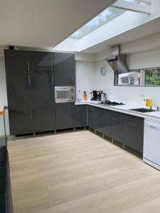 a kitchen with black cabinets and a large window at Huisje aan het water, omgeving Amsterdam in Zaandam