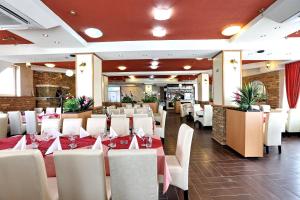 a restaurant with white tables and white chairs at Hotel Novella Uno in Novi Banovci