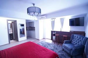 ein Schlafzimmer mit einem roten Bett, einem Stuhl und einem TV in der Unterkunft Luxury 1BR studio near Hanul Drumetului Bucharest in Bukarest