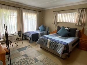 a bedroom with two beds and a table and windows at Tula@159 in Bloemfontein