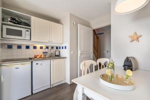 a kitchen with white cabinets and a counter top at Résidence Pierre & Vacances Cap Marine in Le Guilvinec