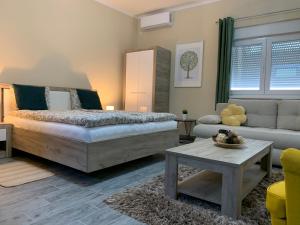 a bedroom with a bed and a couch and a table at Apartman Hana in Sombor