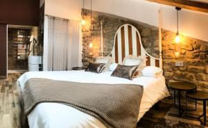 1 dormitorio con 1 cama grande y pared de piedra en La Casona de Alútiz & Bodega, en Samaniego