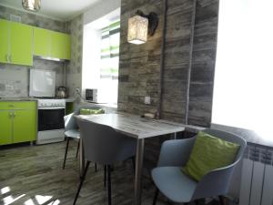 a kitchen with green cabinets and a wooden table and chairs at Apartment WAVE,в центре! in Khmelʼnytsʼkyy