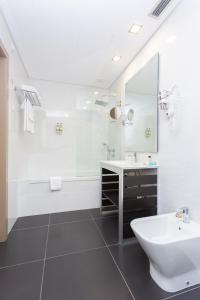 a white bathroom with a sink and a tub at Castelo Santa Catarina in Porto