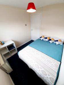 Habitación pequeña con cama y lámpara roja. en Rayleigh Town Centre 3 Bedroom Apartment en Rayleigh