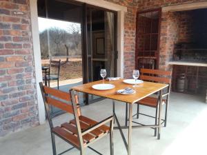 a wooden table with two glasses of wine on a patio at Marloth Wild Fig Studio in Marloth Park +14 photos