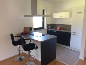 a kitchen with a black island and two bar stools at Ferienwohnung am Ententeich in Bad Marienberg