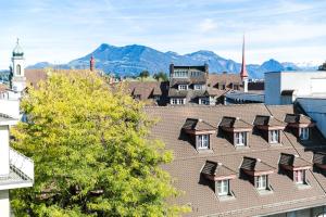a row of roofs on a building with mountains in the background at AirHosted - Lucerne City Centre in Lucerne